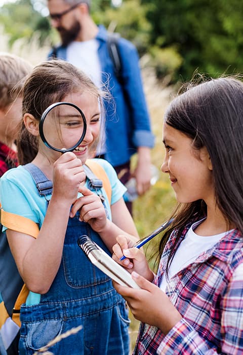 two children smile as they perform a learning activity on a field trip